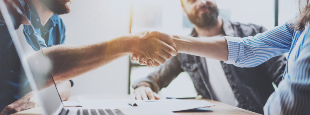 Business partnership handshake concept.Photo two coworkers handshaking process. Successful deal after great meeting. Horizontal, blurred background.Wide